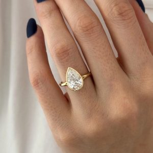 Pear bezel solitaire ring with plain band in yellow tone