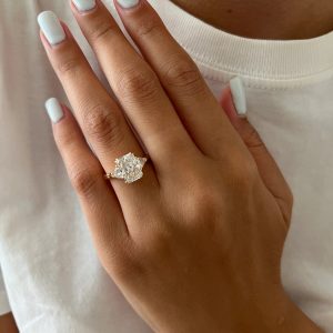 Radiant three-stone engagement ring with triangular side diamonds and double-prong setting