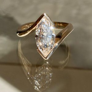 Marquise solitaire engagement ring with bypass shank and partial bezel setting