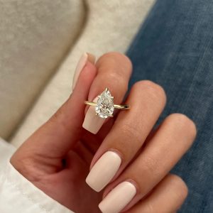 Pear-shaped solitaire engagement ring with a 5-prong basket on a plain rounded band