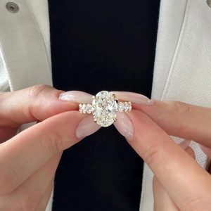 Oval diamond engagement ring with hidden halo and pavé-set diamonds on band