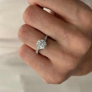 Round diamond engagement ring with split shank and side stone accents