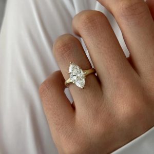 Solitaire engagement ring with marquise center stone and tapered polished shank