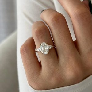 Three-stone engagement ring with oval center and pear side stones on plain shank