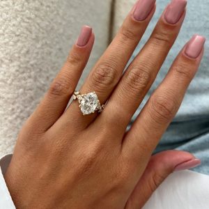 Oval diamond engagement ring with marquise and round accent stones, hidden pavé halo and split intertwining shank.