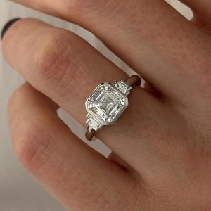 Asscher cut engagement ring with baguette side stones shown on finger