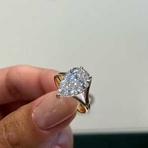 Pear-shaped diamond solitaire engagement ring with multi-prong setting on a plain band