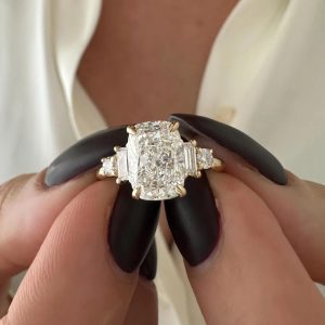 Cushion three-stone engagement ring with baguette and round side accents on a polished band
