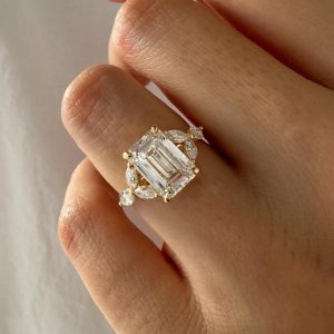 Emerald-cut engagement ring with marquise and round diamond cluster accents