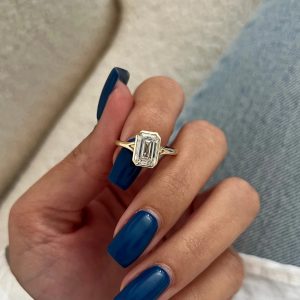 Emerald-cut solitaire engagement ring in bezel setting on a plain band