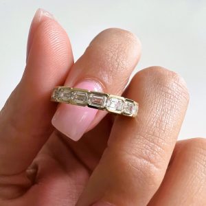 Eternity band with emerald-cut stones in channel setting and four-prong design