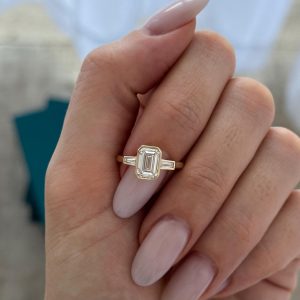 Emerald-cut engagement ring with baguette side stones in a bezel setting