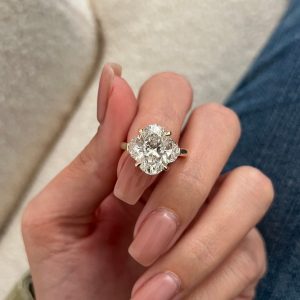 Three-stone engagement ring with cushion diamond and yellow-tone shank