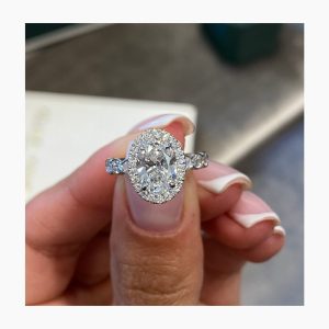 Elegant oval halo engagement ring with side stones on a straight band