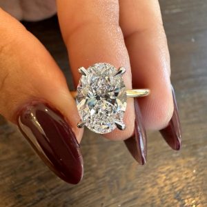 Oval halo engagement ring with raised basket and plain band, four-prong setting