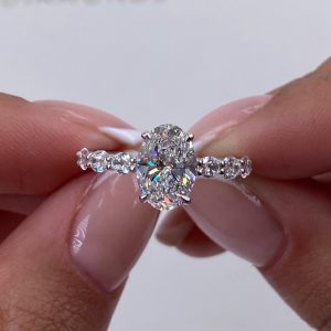 Oval center engagement ring with graduated side diamond band and four prong setting