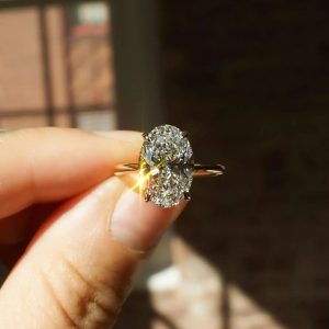 Oval center solitaire engagement ring with contrasting prongs on a plain tapered band