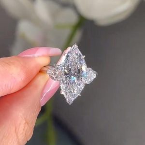 Marquise three-stone engagement ring with pear-shaped side diamonds on a polished band