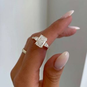 Radiant three-stone engagement ring with pear side diamonds and pavé shank
