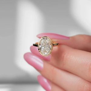 Oval bezel engagement ring with hidden halo and polished band
