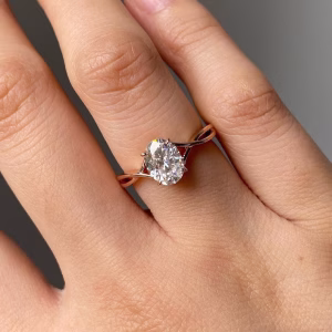 Oval solitaire engagement ring with polished band and cathedral basket setting